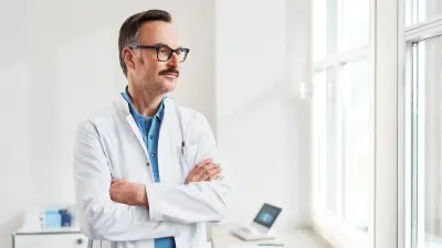 Arzt in Praxis aus dem Fenster schauend, im Hintergrund ist das Vivatmo pro zu sehen.